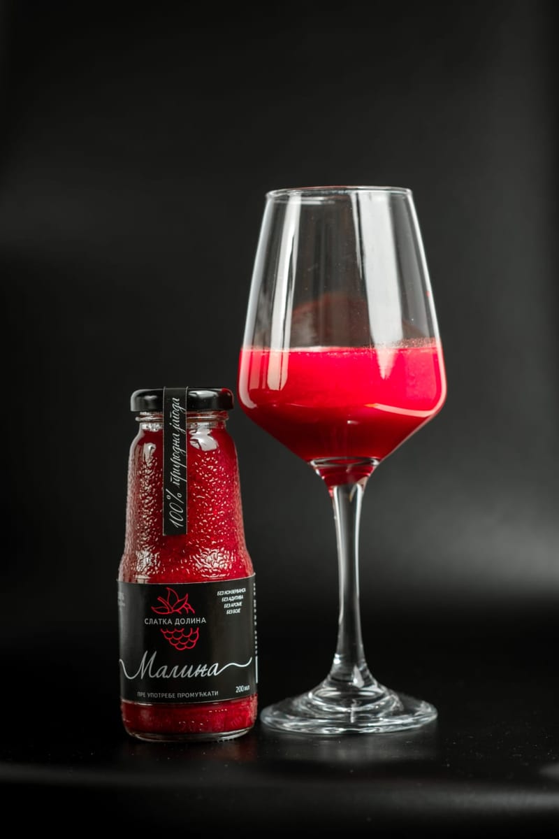 Flašica soka od maline uz punu čašu